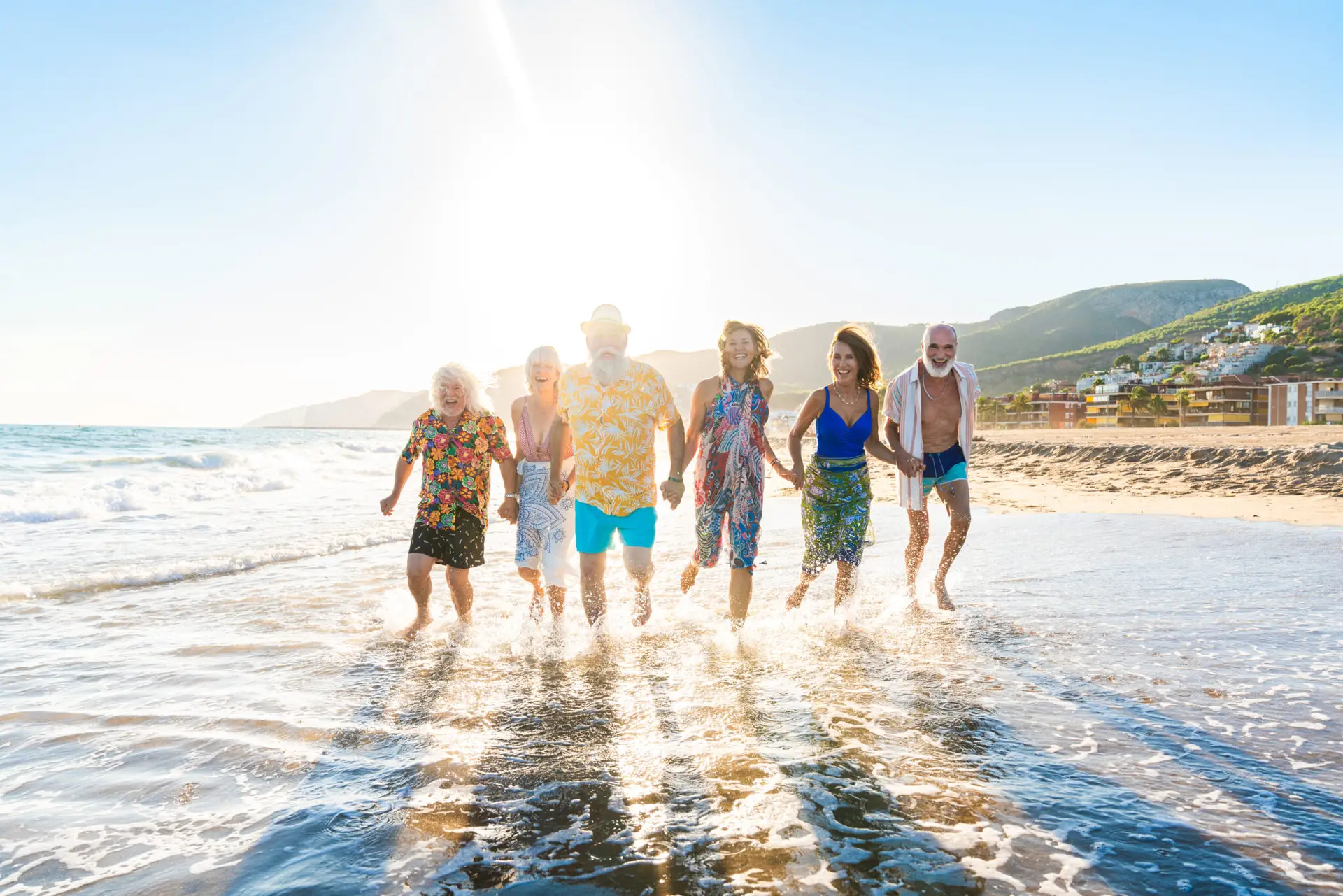 Happy group of senior friends bonding at the beach during summer