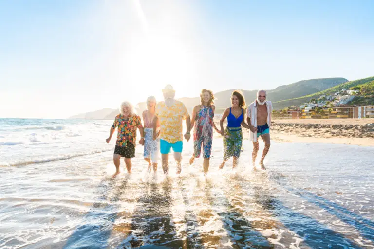 Happy group of senior friends bonding at the beach during summer
